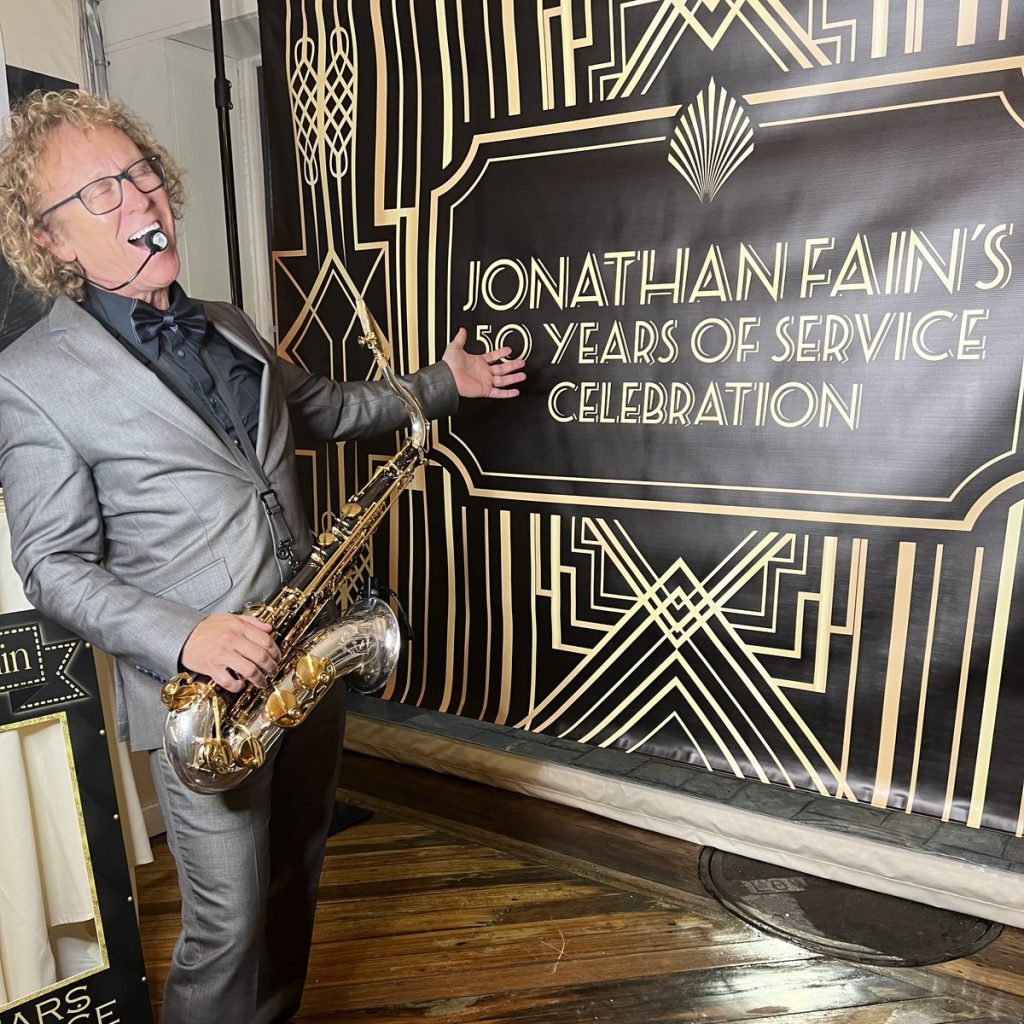 Live saxophone at a corporate 50 years of service celebration, art deco branded banner